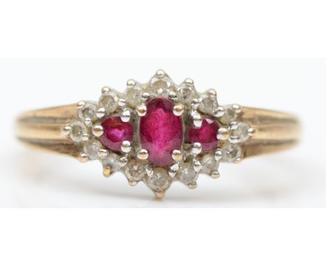 A 9ct gold three stone ruby and diamond cluster ring, the graduated stones bordered by brilliants, Q 1/2, 2.7gmin good condit