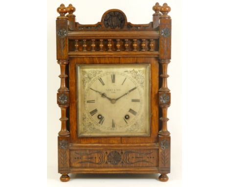An Edwardian oak bracket clock, the case with open fretwork gallery, turned columns and finials with floral carved decoration
