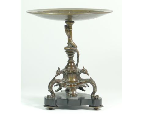 A bronze tazza, the tripod base of sphinxes with climbing snake on a central baluster upright, raised on a marble base. H18cm