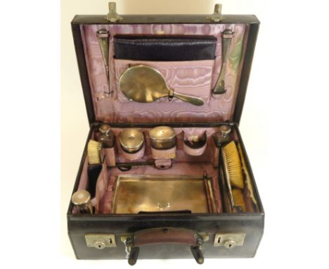 A ladies leather travel case, containing a silver and glass dressing table set, London 1918, with engine turned decoration, s