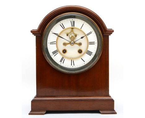 An Edwardian mahogany cased mantel clock, the circular enamel dial with blued steel hands and a visible escapement with Roman