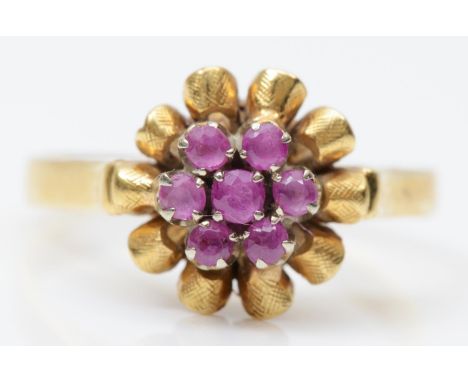 An 18K gold and ruby cluster ring, with scroll border, Q, 4.8gm 