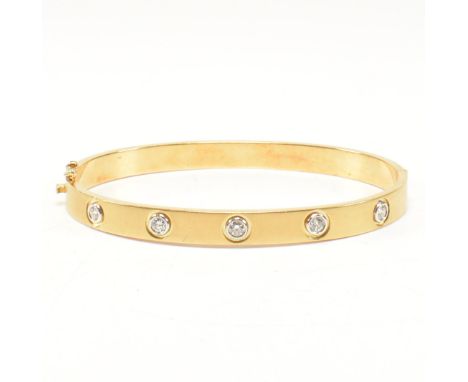 A gold and diamond hinged bangle. The bangle set with five round brilliant cut diamonds to a satin textured hinged band. Mark