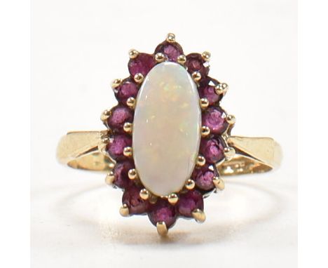 A hallmarked 9ct gold, opal and ruby cluster ring. The ring having a central opal cabochon surrounded by a halo of round cut 