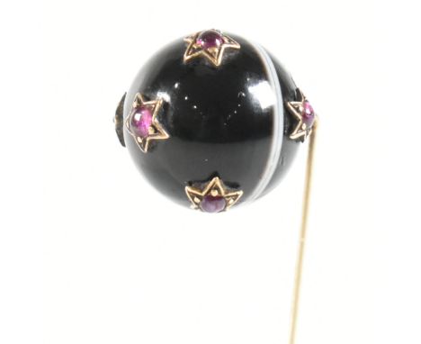 A banded agate and ruby set gold stick pin. The stick pin having a sphere of banded agate with seven star set ruby cabochons 