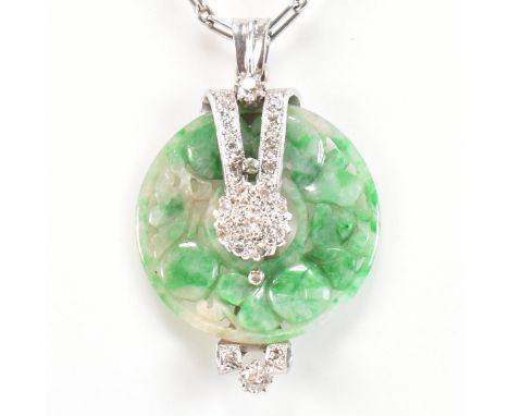 A 1920s platinum, jade and diamond carved pendant necklace. The necklace having a carved round jade pendant held in a platinu