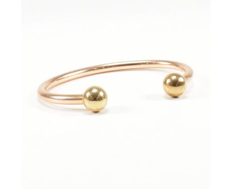 A hallmarked 9ct gold bangle bracelet. The torque cuff bangle having ball terminals to each end and having a halo band. Hallm