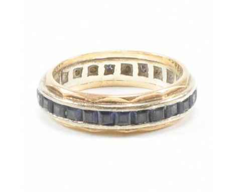 A vintage yellow metal and sapphire eternity ring. The band ring having a continuous row of square cut sapphires to an invert
