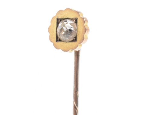 An antique yellow metal and white stone stick pin. The pin having a scalloped circular head with square set round cut white s