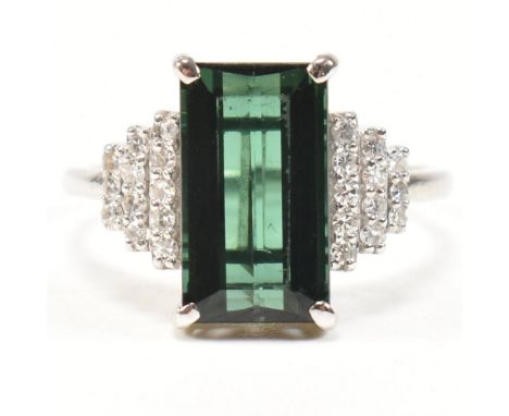 An 18ct white gold, tourmaline and diamond ring. The ring set with a central emerald cut tourmaline with stepped diamond set 