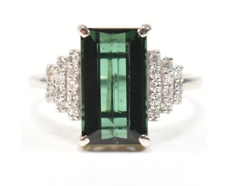 An 18ct white gold, tourmaline and diamond ring. The ring set with a central emerald cut tourmaline with stepped diamond set 