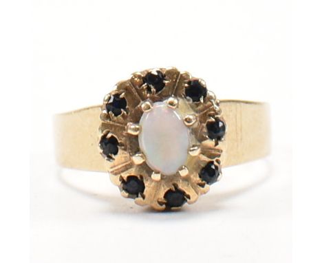 A hallmarked 9ct gold, sapphire and opal cluster ring. The ring set with a central opal cabochon and eight round cut sapphire