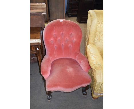 Victorian pink velour upholstered button back small arm or nursing chair raised on short scrolled legs with later casters, 81