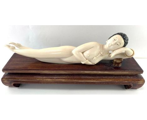 An ivory figure of a nude, reclining on a wooden base, the figure with black hair, and wearing jewellery including a bangle, 