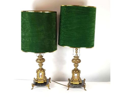 A pair of 20th century gilt metal lamps, each standing on a black square marble base, with four ceramic panels each decorated