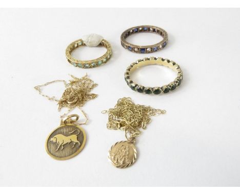 A Taurus pendant marked '9ct' on a chain, a St Christopher on a chain; and three unmarked full eternity rings, two set with s