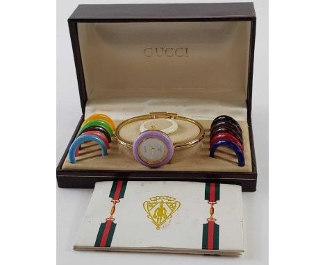 A Gucci ladies gold plated bangle wrist watch , with interchangeable plastic bezels, boxed
