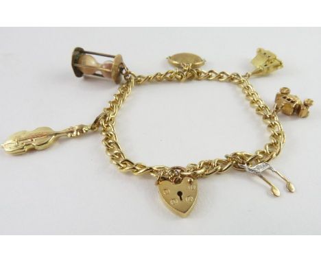 A curb link charm bracelet stamped '375', with heart padlock and safety chain, with various charms attached to include a chur
