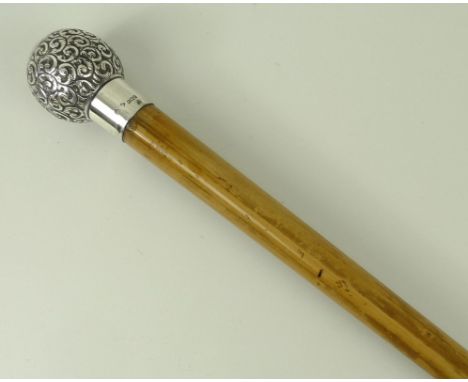 An Edwardian malacca walking stick with a silver knop embossed with scrolling leaves, reserve monogram engraved, London 1904,