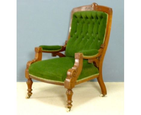 A Victorian mahogany framed open armchair upholstered in green button back velour, raised on turned legs and ceramic castors,