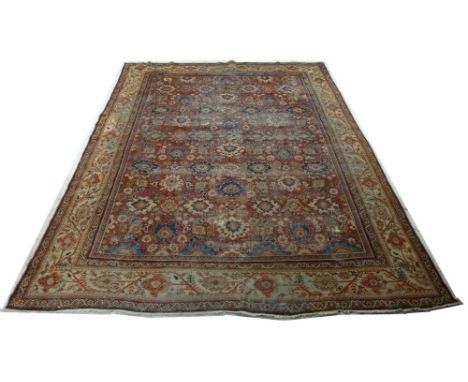 An antique Middle Eastern carpet, the red ground with multiple repeating floral pattern of white, blue, red and beige, wide b