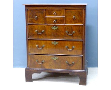 An early 18th century walnut chest of seven drawers, cross banded and with brass handles and escutcheons, raised on bracket f
