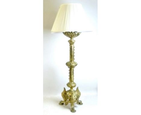 A brass church candlestick on a tripod base, converted to a table lamp, with cream shade, 102cm high.