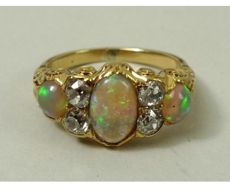 A 19th century opal and diamond five stone ring of three cabochon opals divided by two pairs of diamonds, in a scrolled setti