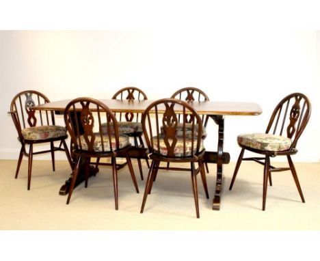 An Ercol trestle dining table, dark stained, 182 by 80 by 73cm high, and six Windsor chairs, including two carvers, each 62 b