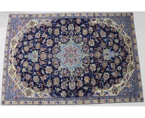 A silk central Persian carpet with a dark blue ground, central eight pointed star medallion in light blue, light green and gr