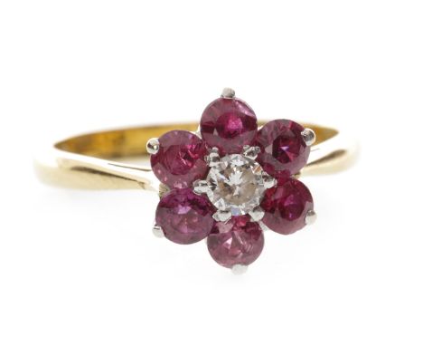 RUBY AND DIAMOND CLUSTER RING set with a central round brilliant cut diamond of approximately 0.08 carats surrounded by round