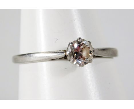 A solitaire dress ring, with round brilliant cut white stone, in claw setting with pierced shoulders on a white metal band, u