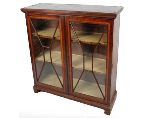 An Edwardian mahogany display cabinet, the over run top with a satinwood crossbanding, raised above two astragal glazed doors