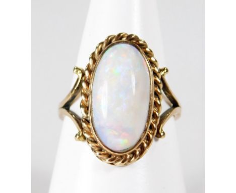 A single stone opal dress ring, with oval cabochon cut opal in twist design border, with pierced design shoulders, yellow met