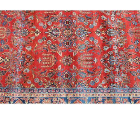 A 20thC woolen carpet, in geometric floral pattern, predominately in red and blue, 495cm x 267cm.