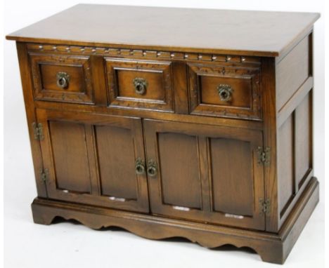 A 20thC Old Charm style side cabinet, the over run top raised above three drawers and a double panelled cupboard, on bracket 