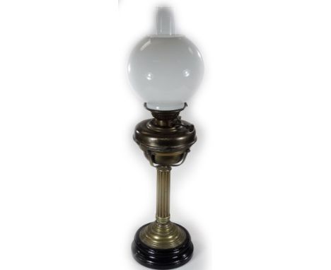 A late 19thC brass oil lamp, with plain glass chimney, milk glass globular shade and reeded stem, on an inverted circular bas