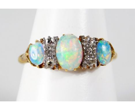 An 18ct gold opal and diamond ring, set with three opals and six tiny diamonds, in raised claw setting, with scroll design sh