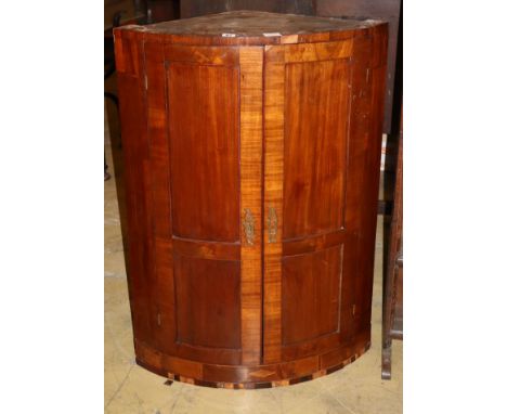 A Regency banded mahogany bow fronted hanging corner cupboard (a.f.), W.70cm, D.44cm, H.100cm