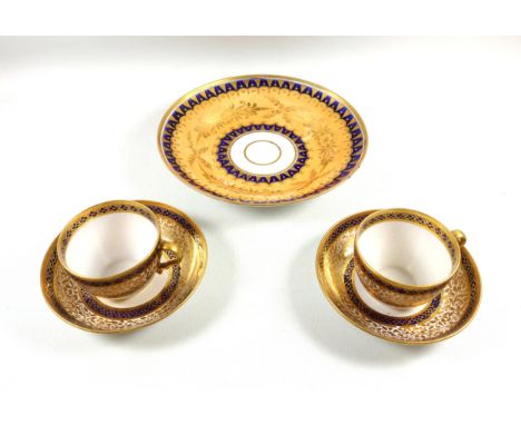 Pair of Regency Worcester cups and saucers, each with painted gilt foliate and blue lozenge bands, D.13.4cm, and a gilt flora