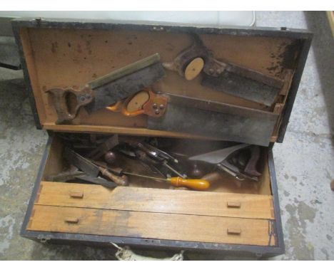 A vintage toolbox containing woodworking planes, saws, drill pieces and other items 