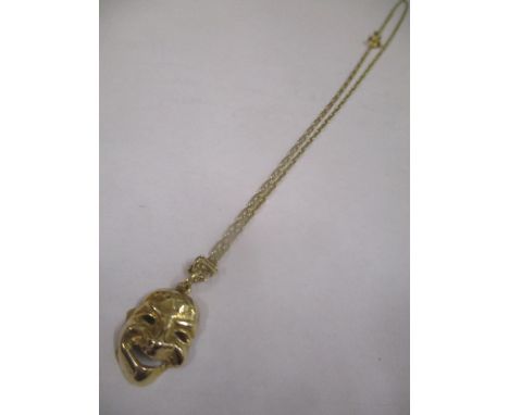 A gold coloured necklace stamped 750 and a mask pendant, the ring stamped 585, 5g total 