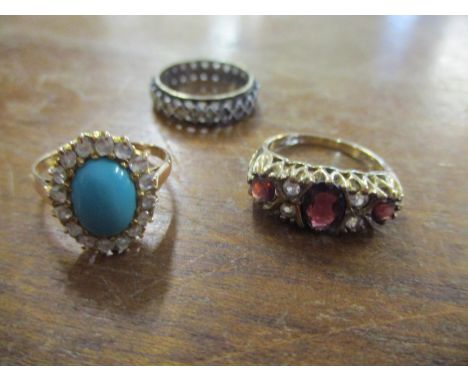 A 9ct gold garnet and white sapphire ring, a yellow metal turquoise cabochon ring surrounded by white stones, and a silver et