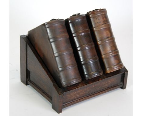 SET OF THREE ROYAL DOULTON BOOK PATTERN WHISKY FLASKS WITH HALLMARKED SILVER CORK TOPS AND SPOUTS, housed in an oak book rack