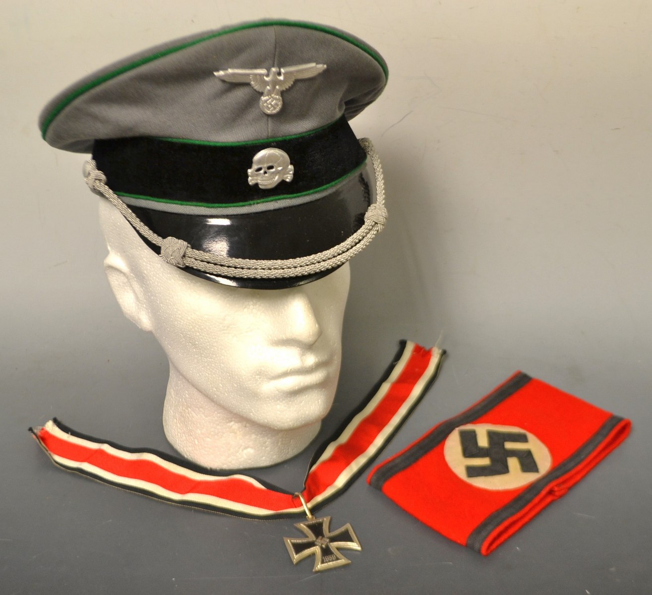 Militaria a Nazi Germany style dress hat, Skull and cross bones badge, Arm Band and iron cross,