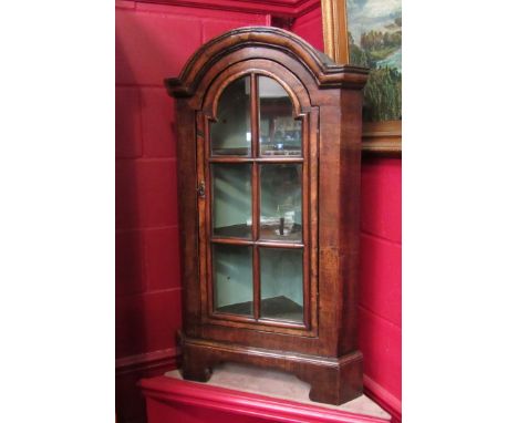 A George II style walnut dome top free standing corner cabinet the panel glazed door with key and painted interior over brack