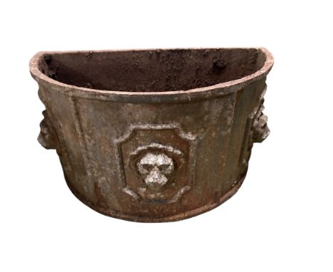 A demi lune lead style iron wall planter with lion mask faces, an iron classical pedestal