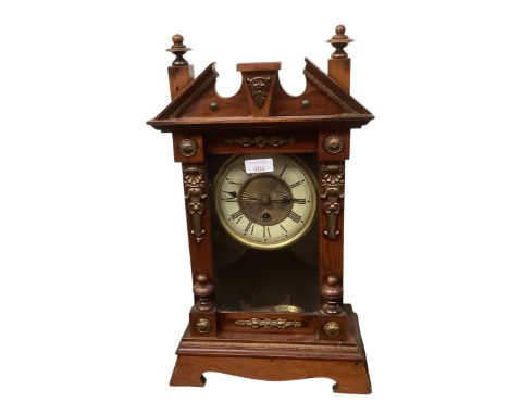 A mahogany mantle clock with broken arch pediment, and brass mounts and a brass circular dial with black Roman Numerals