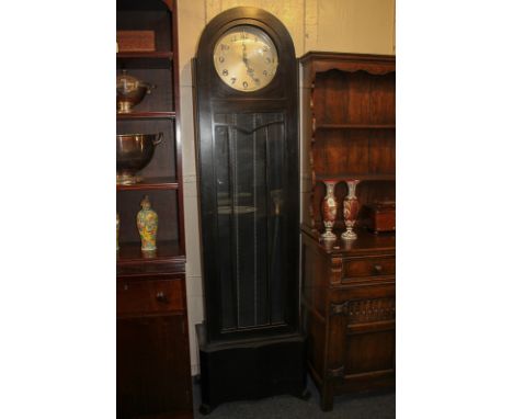 An Art Deco style long case clock in domed ebonised case, the circular dial with silverised Arabic numerals, striking on West
