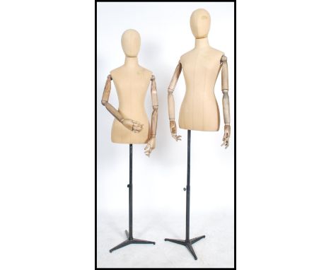 A pair of 20th century shop haberdashery mannequins of female form being linen covered and with wooden articulated arms and h